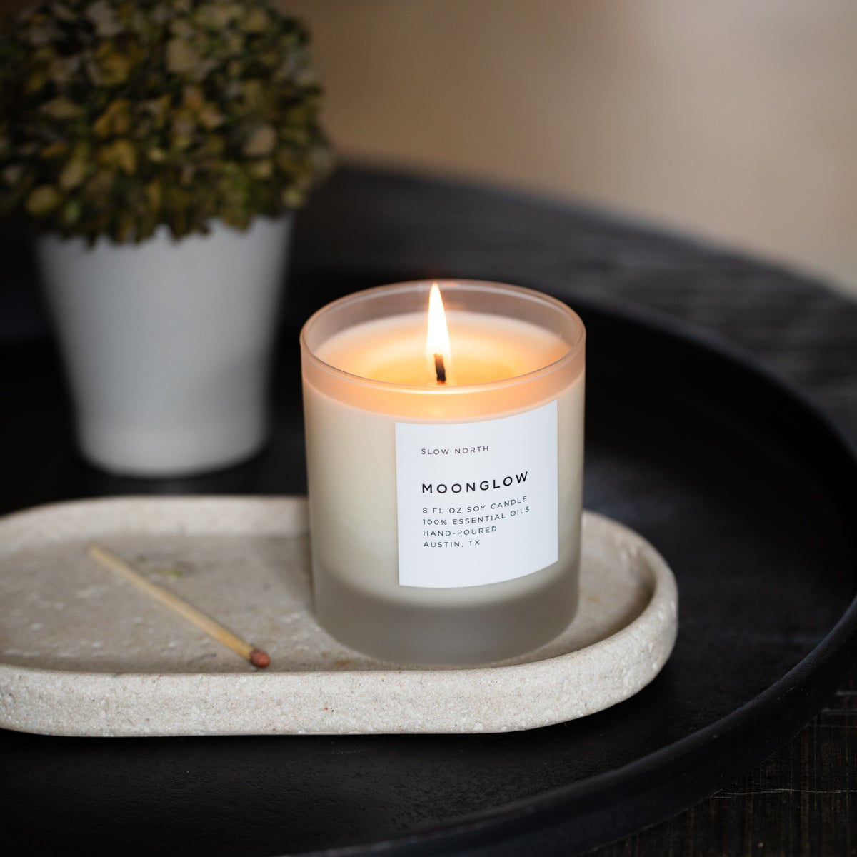 Candle labeled 'Moonglow' on a tray with a blurred background