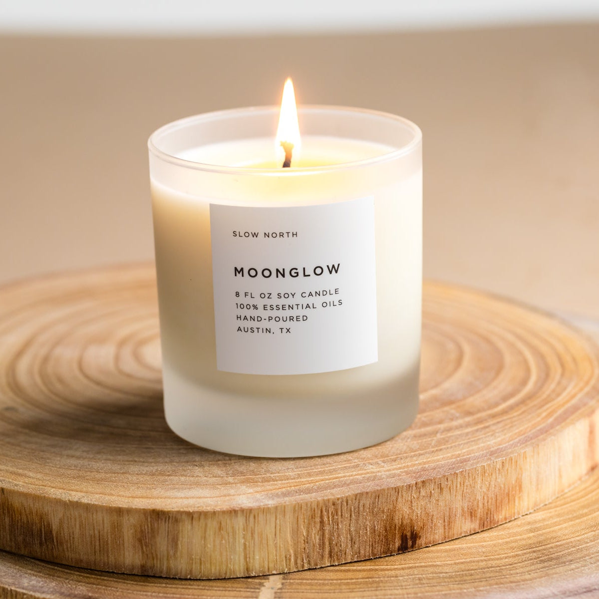 Candle labeled 'Moonglow' on a wooden surface