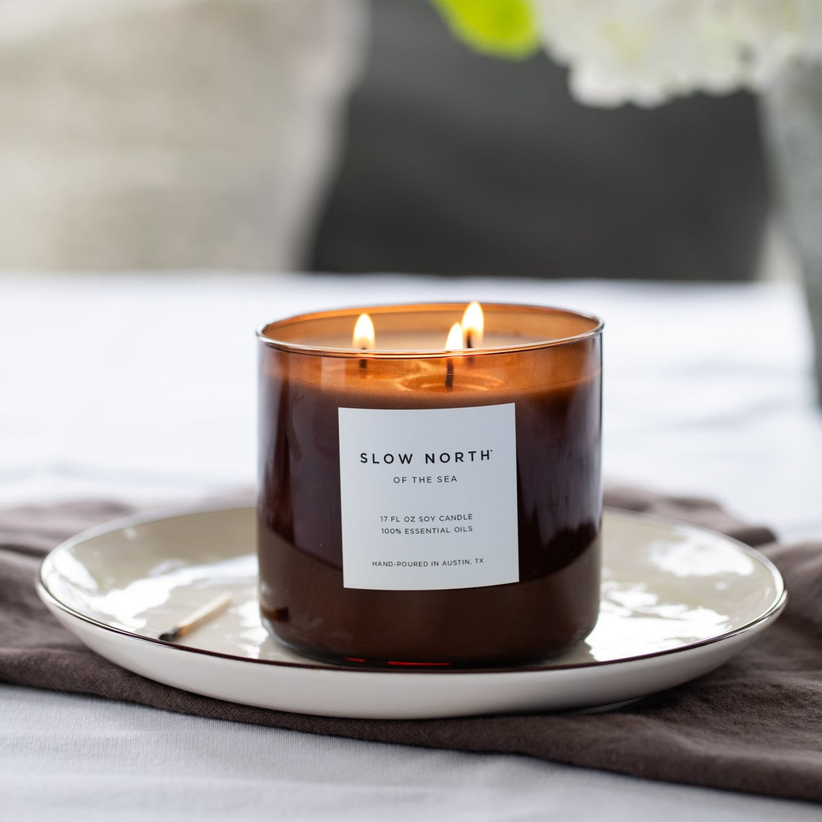 Candle with a label on a white plate in a home setting